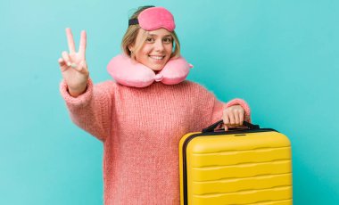 Güzel sarışın kadın gülümsüyor ve arkadaş canlısı görünüyor. İki numarayı gösteriyor. uçuş yolcu kavramı