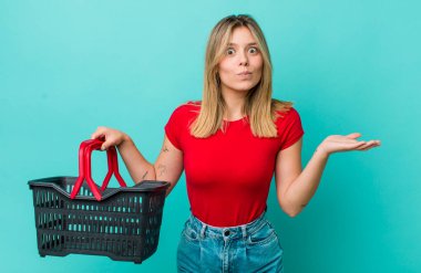 Güzel sarışın kadın şaşkın, şaşkın ve şüpheci hissediyor. Alışveriş sepeti konsepti