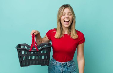 Güzel sarışın kadın agresif bir şekilde bağırıyor, çok kızgın görünüyor. Alışveriş sepeti konsepti