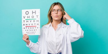 Güzel sarışın kadın şaşkın ve kafası karışık, kaşınıyor. optik görüş testi konsepti