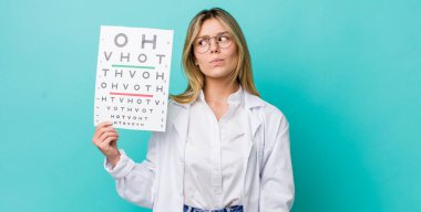 Güzel sarışın kadın omuz silkiyor, kafası karışık ve kararsız. optik görüş testi konsepti