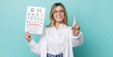 Güzel sarışın kadın gururla gülümsüyor ve kendinden emin bir numara oluyor. optik görüş testi konsepti