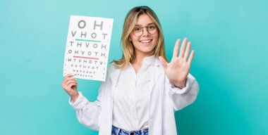 Güzel sarışın kadın gülümsüyor ve arkadaş canlısı görünüyor, beş numarayı gösteriyor. optik görüş testi konsepti