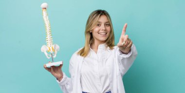 Güzel sarışın kadın gülümsüyor ve arkadaş canlısı görünüyor. Bir numarayı gösteriyor. Omurga uzmanı konsepti