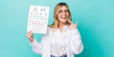 Güzel sarışın kadın kendi gülüşünü göstererek kendine güvenerek gülümsüyor. optik görüş testi konsepti