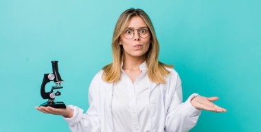 Güzel sarışın kadın şaşkın, şaşkın ve şüpheci hissediyor. Bilim adamı ve mikroskop kavramı