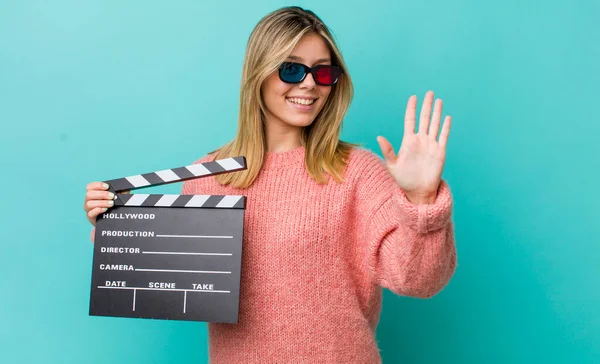 Güzel sarışın kadın gülümsüyor ve arkadaş canlısı görünüyor, beş numarayı gösteriyor. Sinema kavramı
