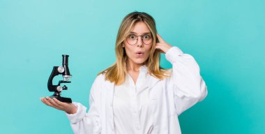 Güzel sarışın kadın şaşırmış görünüyor, yeni bir düşünce, fikir ya da konsept fark ediyor. Bilim adamı ve mikroskop kavramı