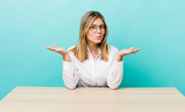 Güzel sarışın kadın şaşkın, şaşkın ve şüpheci hissediyor. iş ve masa konsepti