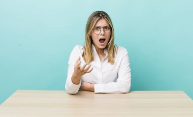 Güzel sarışın kadın sinirli, sinirli ve sinirli görünüyor. iş ve masa konsepti