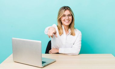 Güzel sarışın kadın seni seçen kamerayı işaret ediyor. iş ve masa konsepti