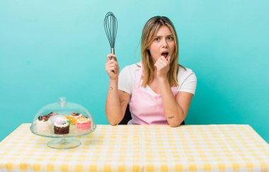 Güzel sarışın kadın, ağzı ve gözleri sonuna kadar açık ve eli çenesinde. Ev yapımı kek konsepti