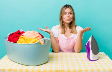 Güzel sarışın kadın şaşkın, şaşkın ve şüpheci hissediyor. Demir ve giysi konsepti