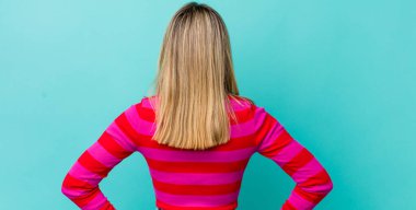 Genç, güzel, sarışın bir kadın kafası karışık ya da dolgun ya da şüphe ve soru dolu, merak ediyor, elleri kalçasında, dikiz aynasından.