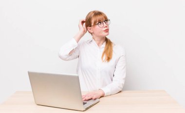 Kızıl saçlı güzel kadın şaşkın ve kafası karışık, kaşınan bir kafa hissediyor. iş kavramı