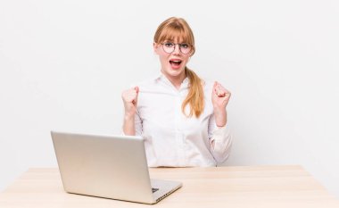 Kızıl saçlı güzel kadın şok olmuş hissediyor, gülüyor ve başarıyı kutluyor. iş kavramı