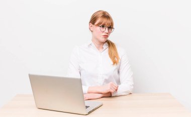 Kızıl saçlı, güzel bir kadın üzgün, üzgün ya da kızgın ve yana bakıyor. iş kavramı