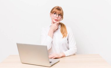 Kızıl saçlı güzel kadın düşünüyor, kuşkulu ve şaşkın hissediyor. iş kavramı