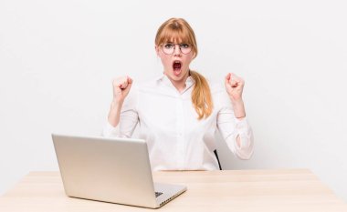 Kızıl saçlı güzel bir kadın sinirli bir ifadeyle agresif bir şekilde bağırıyor. iş kavramı