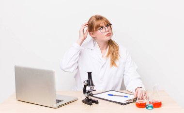 Kızıl saçlı güzel kadın şaşkın ve kafası karışık, kaşınan bir kafa hissediyor. Mikroskobik bilim adamı.