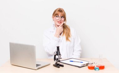 Kızıl saçlı, güzel bir kadın mutlu, kendinden emin, elleri çenesinde gülümsüyor. Mikroskobik bilim adamı.