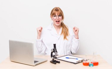 Kızıl saçlı güzel kadın şok olmuş hissediyor, gülüyor ve başarıyı kutluyor. Mikroskobik bilim adamı.