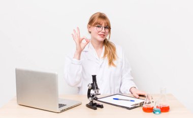 Kızıl saçlı güzel bir kadın kendini mutlu hissediyor. Onayını iyi bir hareketle gösteriyor. Mikroskobik bilim adamı.