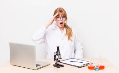 Kızıl saçlı güzel kadın mutlu, şaşkın ve şaşırmış görünüyor. Mikroskobik bilim adamı.