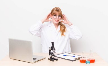 Kızıl saçlı güzel kadın stresli, endişeli ya da korkmuş, elleri başının üstünde. Mikroskobik bilim adamı.