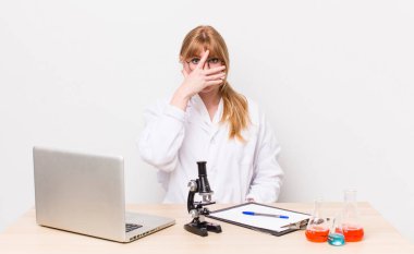 Kızıl saçlı güzel bir kadın şok olmuş, korkmuş ya da korkmuş görünüyor. Mikroskobik bilim adamı.