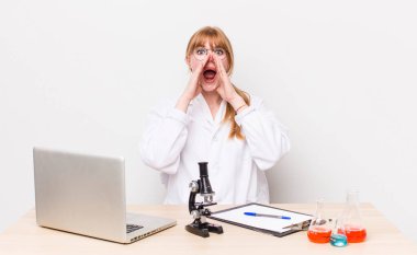 Kızıl saçlı, güzel bir kadın kendini mutlu hissediyordu. Elleri ağzının kenarında bağırıyordu. Mikroskobik bilim adamı.