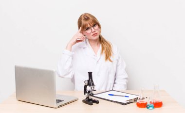 Kızıl saçlı güzel kadın kafası karışık ve şaşkın hissediyor, deli olduğunu gösteriyor. Mikroskobik bilim adamı.