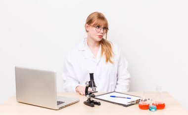 Kızıl saçlı, güzel bir kadın üzgün, üzgün ya da kızgın ve yana bakıyor. Mikroskobik bilim adamı.