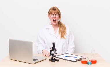 Kızıl saçlı, güzel bir kadın agresif bir şekilde bağırıyor, çok kızgın görünüyor. Mikroskobik bilim adamı.