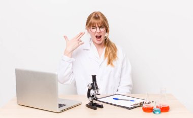 Kızıl saçlı güzel bir kadın mutsuz ve stresli görünüyor, intihar jesti silah işareti yapıyor. Mikroskobik bilim adamı.