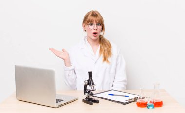 Kızıl saçlı, güzel bir kadın şaşırmış ve şok olmuş görünüyor. Çenesi düşmüş, elinde bir nesne var. Mikroskobik bilim adamı.