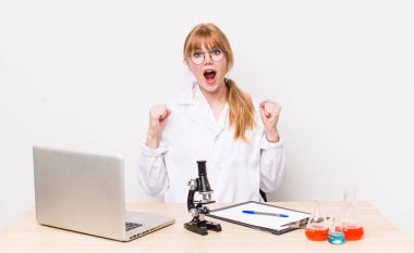 Kızıl saçlı güzel bir kadın sinirli bir ifadeyle agresif bir şekilde bağırıyor. Mikroskobik bilim adamı.