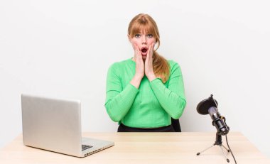 Kızıl saçlı güzel kadın şok olmuş ve korkmuş hissediyor. dizüstü bilgisayar ve mikrofon kavramı