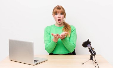 Kızıl saçlı güzel kadın umutsuz, hayal kırıklığına uğramış ve stresli görünüyor. dizüstü bilgisayar ve mikrofon kavramı