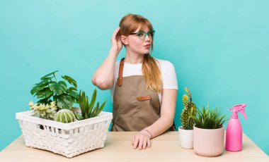 Kızıl saçlı güzel kadın şaşkın ve kafası karışık, kaşınan bir kafa hissediyor. bitkiler gargara konsepti