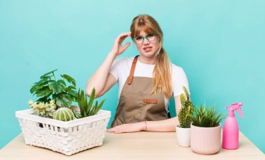 Kızıl saçlı güzel kadın kafası karışık ve şaşkın hissediyor, deli olduğunu gösteriyor. bitkiler gargara konsepti