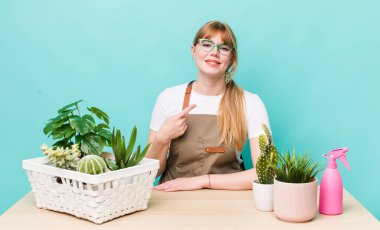 Kızıl saçlı güzel bir kadın neşeyle gülümsüyor, mutlu hissediyor ve bir tarafı işaret ediyor. bitkiler gargara konsepti