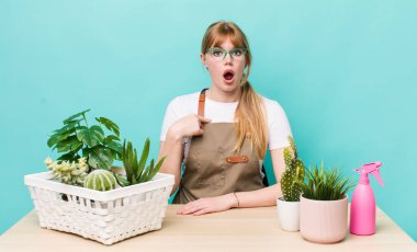 Kızıl saçlı güzel kadın şok olmuş ve ağzı açık, kendini işaret eden bir şekilde şaşırmış görünüyor. bitkiler gargara konsepti