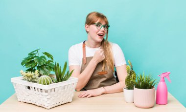 Kızıl saçlı güzel bir kadın kendini mutlu hissediyor ve bir meydan okumayla yüzleşiyor ya da kutluyor. bitkiler gargara konsepti