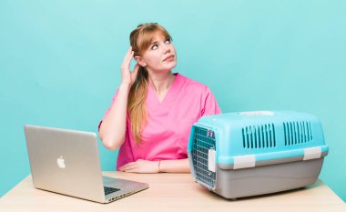 Kızıl saçlı güzel kadın mutlu bir şekilde gülümsüyor ve hayal kuruyor ya da şüphe ediyor. Veterinerlik kavramı