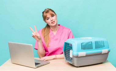 Kızıl saçlı güzel kadın gülümsüyor ve mutlu görünüyor, zafer ya da barış işareti yapıyor. Veterinerlik kavramı