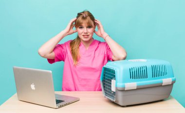 Kızıl saçlı güzel kadın stresli, endişeli ya da korkmuş, elleri başının üstünde. Veterinerlik kavramı