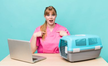 Kızıl saçlı güzel bir kadın mutlu hissediyor ve heyecanla kendini işaret ediyor. Veterinerlik kavramı