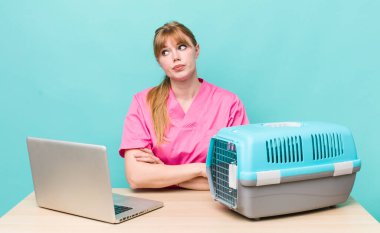 Kızıl saçlı güzel kadın omuz silkiyor, kafası karışık ve kararsız. Veterinerlik kavramı