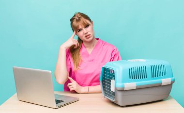 Kızıl saçlı güzel kadın kafası karışık ve şaşkın hissediyor, deli olduğunu gösteriyor. Veterinerlik kavramı